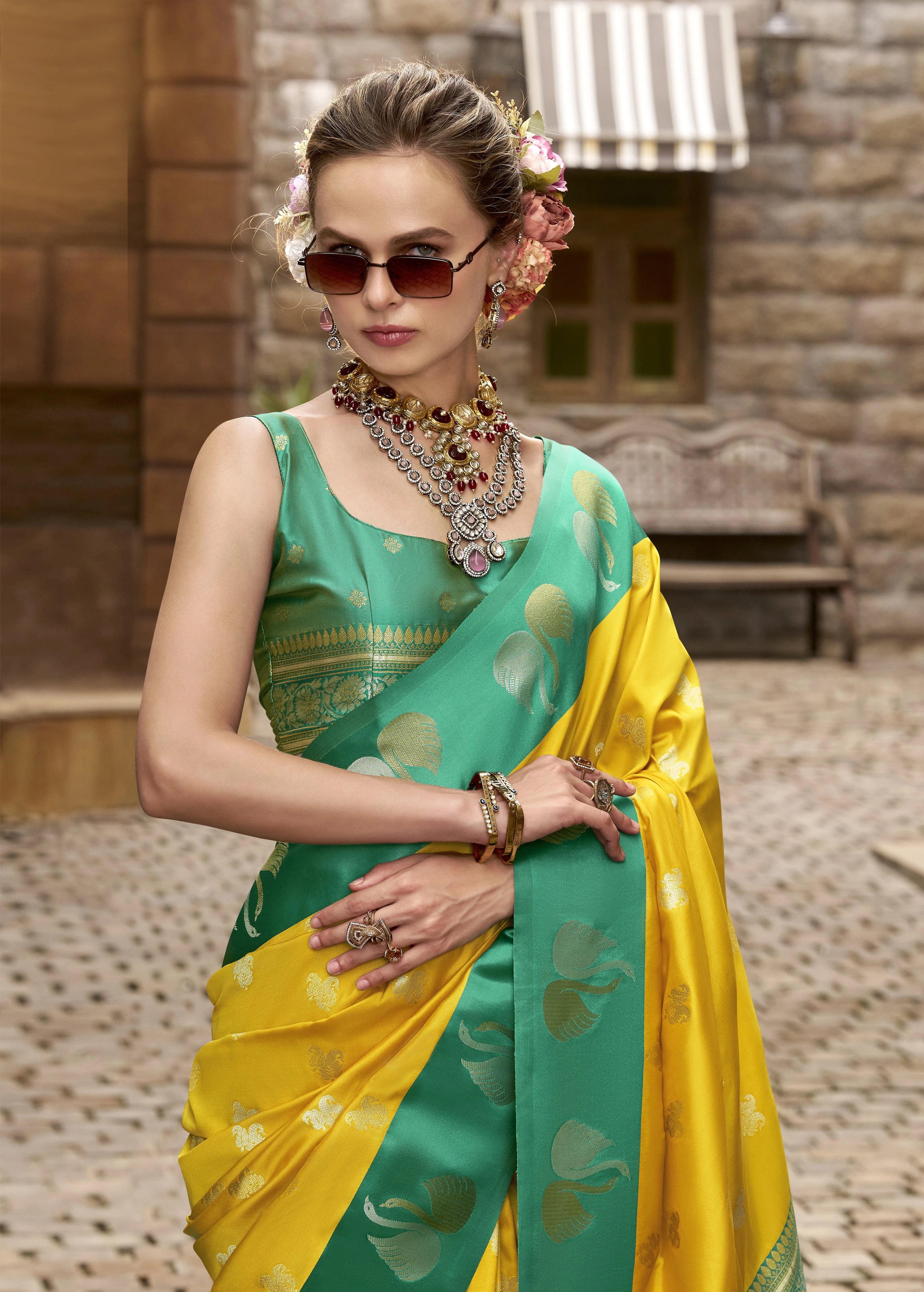 Woman wearing a green and yellow saree with jewelry in an outdoor setting