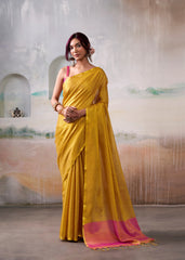 Woman wearing a yellow saree with pink border against an artistic background