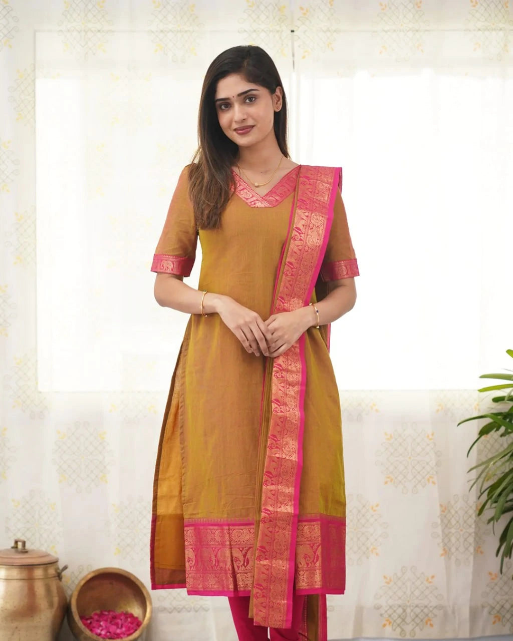 Woman wearing a mustard yellow and pink traditional outfit with a white background