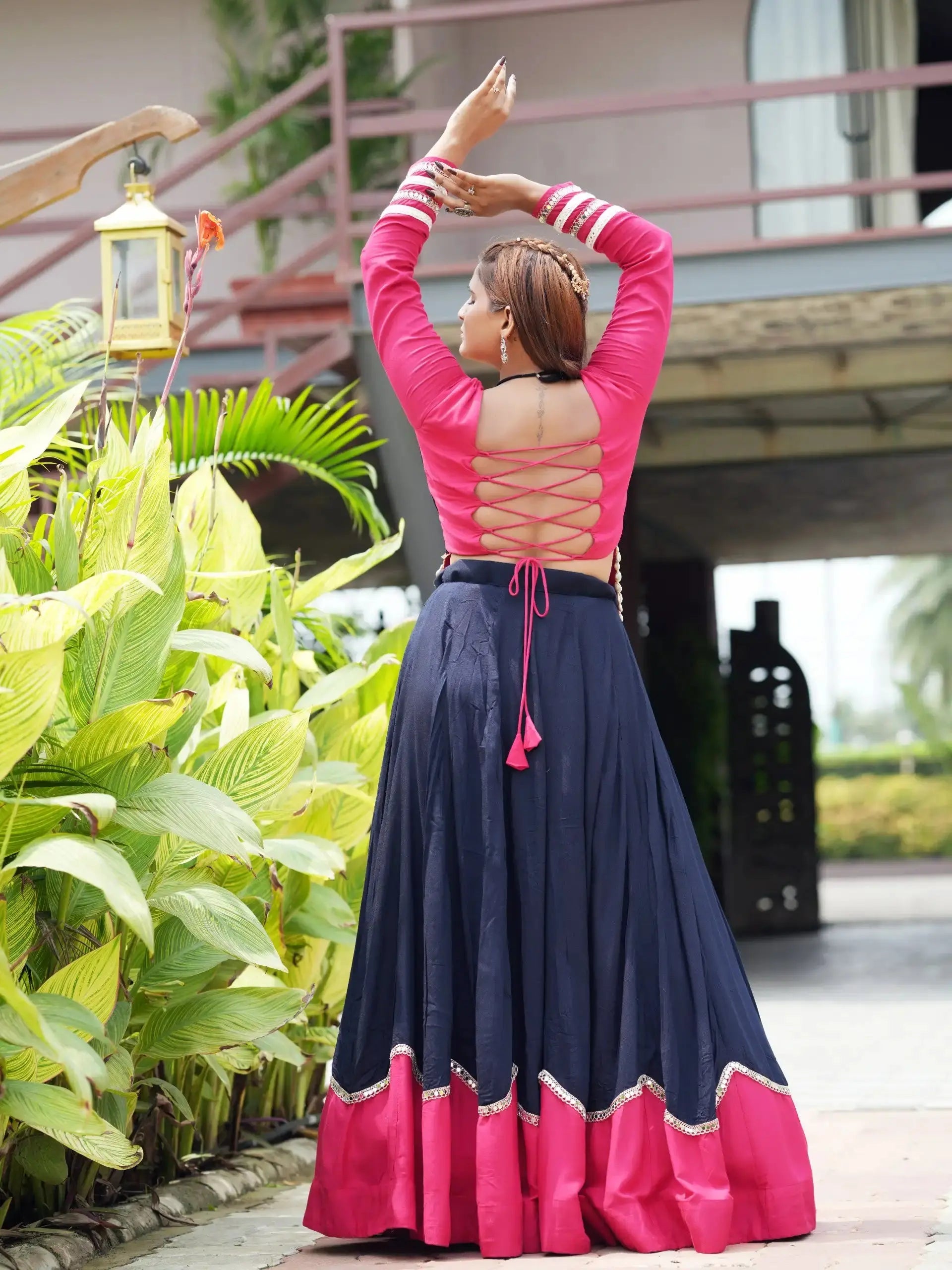 Back view of navy blue lehenga showing pink corset lace-up choli and circular skirt with pink hem
