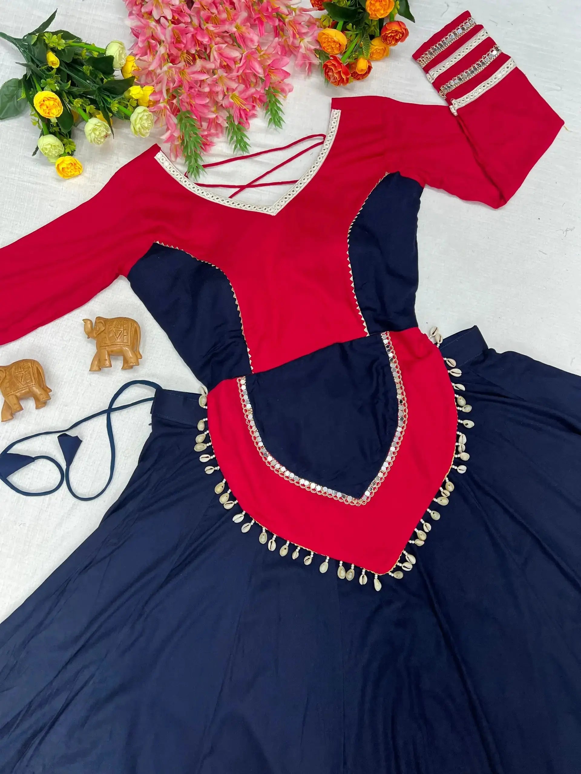 Flat lay of navy blue lehenga with pink embroidered choli, cowrie shell peplum and full skirt spread