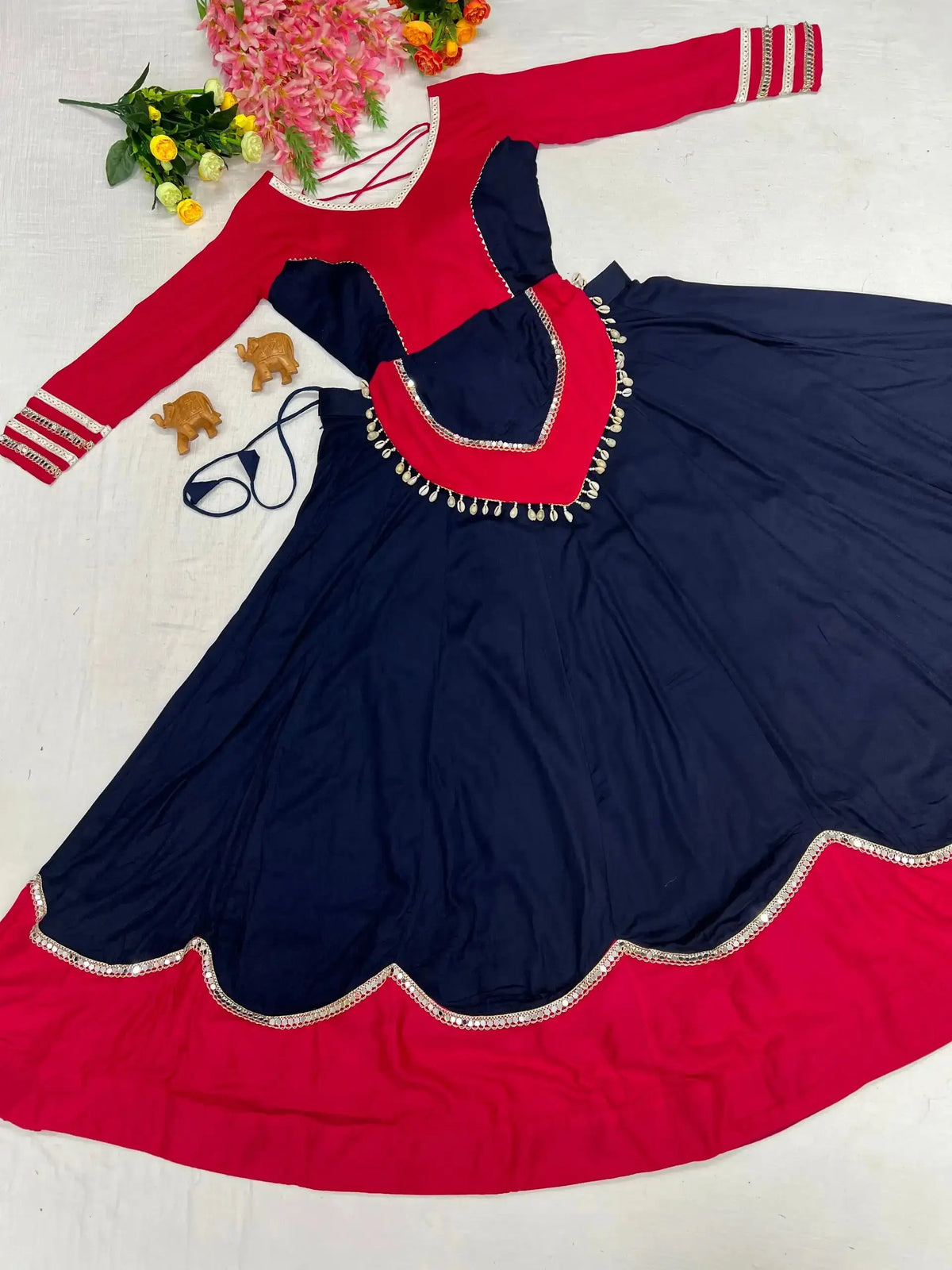 Flat lay of full navy blue mirror lace work lehenga set with pink choli and cowrie shell peplum overlay