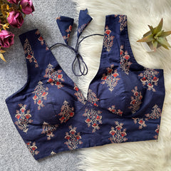 Navy blue embroidered top on a textured surface with flowers and a plant in the background