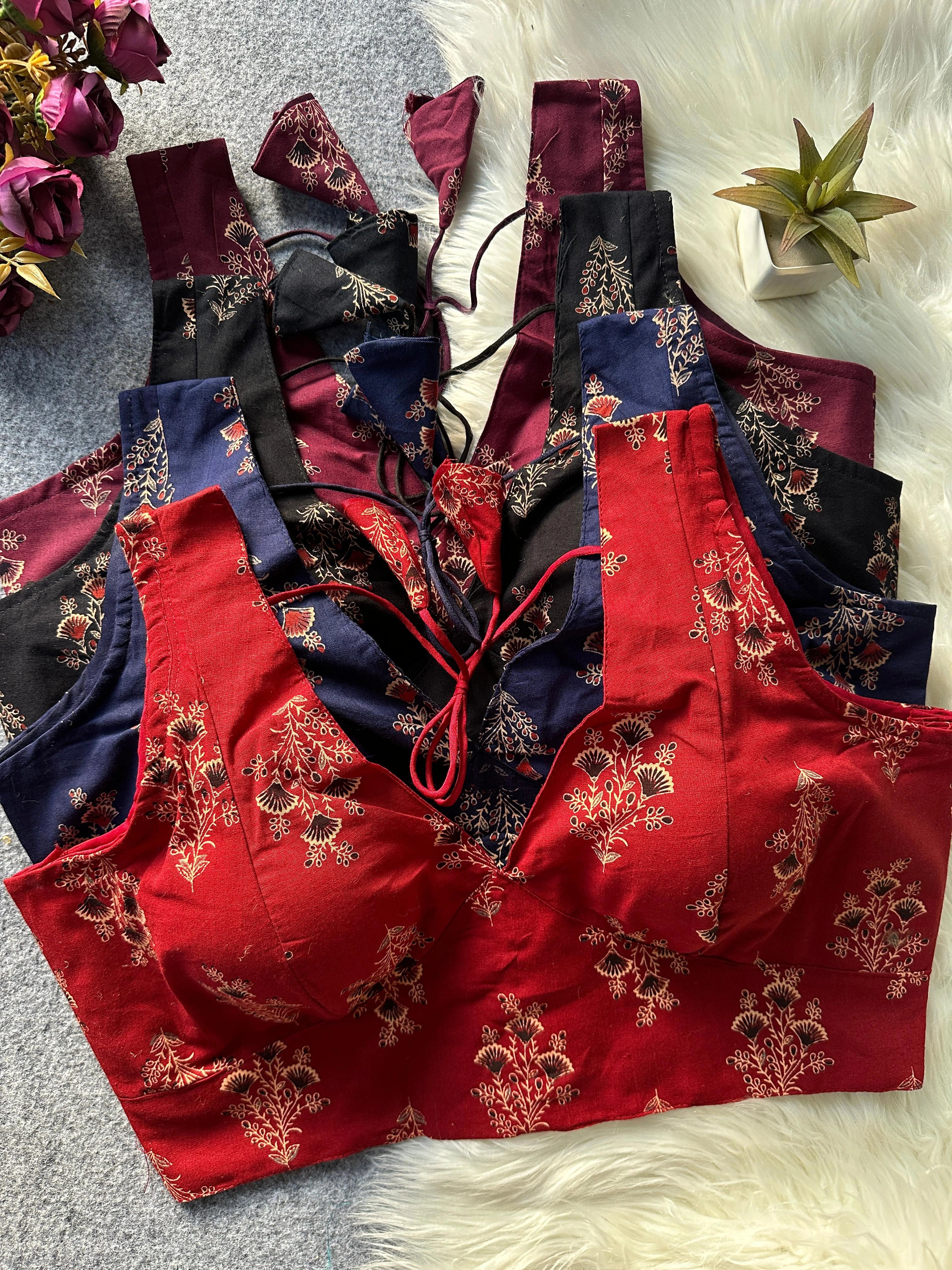 Red floral lingerie set on a textured surface with flowers and a plant in the background