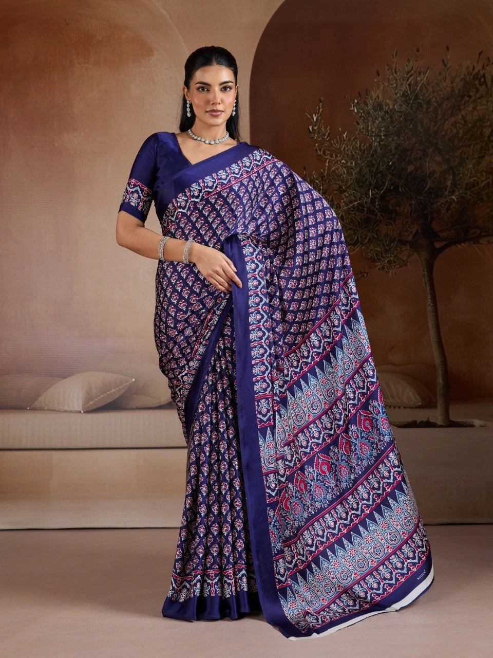 Woman wearing a blue and purple patterned saree in an indoor setting.
