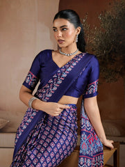 Woman wearing a blue saree with pink patterns in an indoor setting