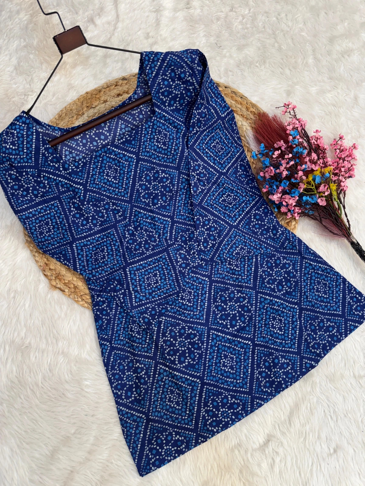 Blue patterned top on a hanger with a white background
