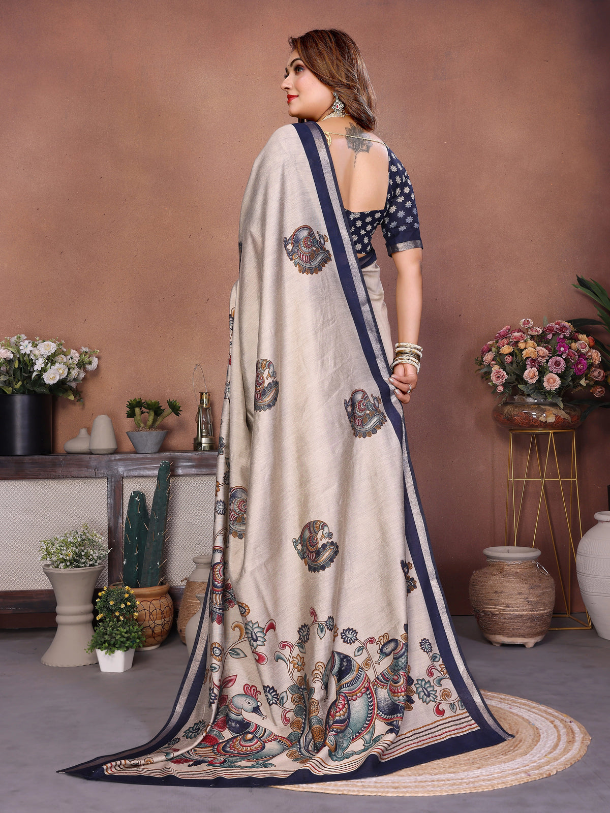 Woman wearing a saree with a floral pattern in a decorated room.