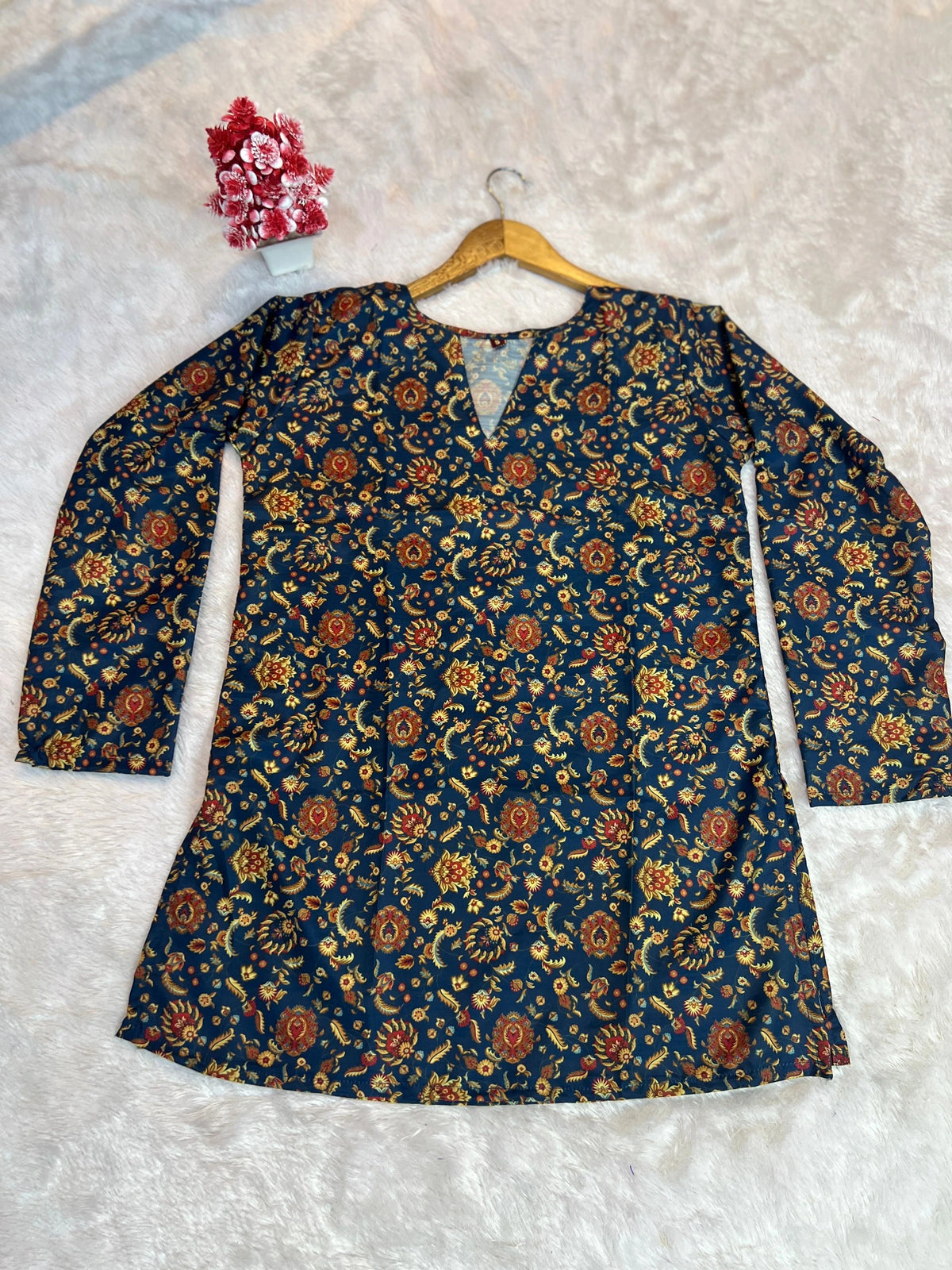 Floral patterned top on a hanger against a textured white background