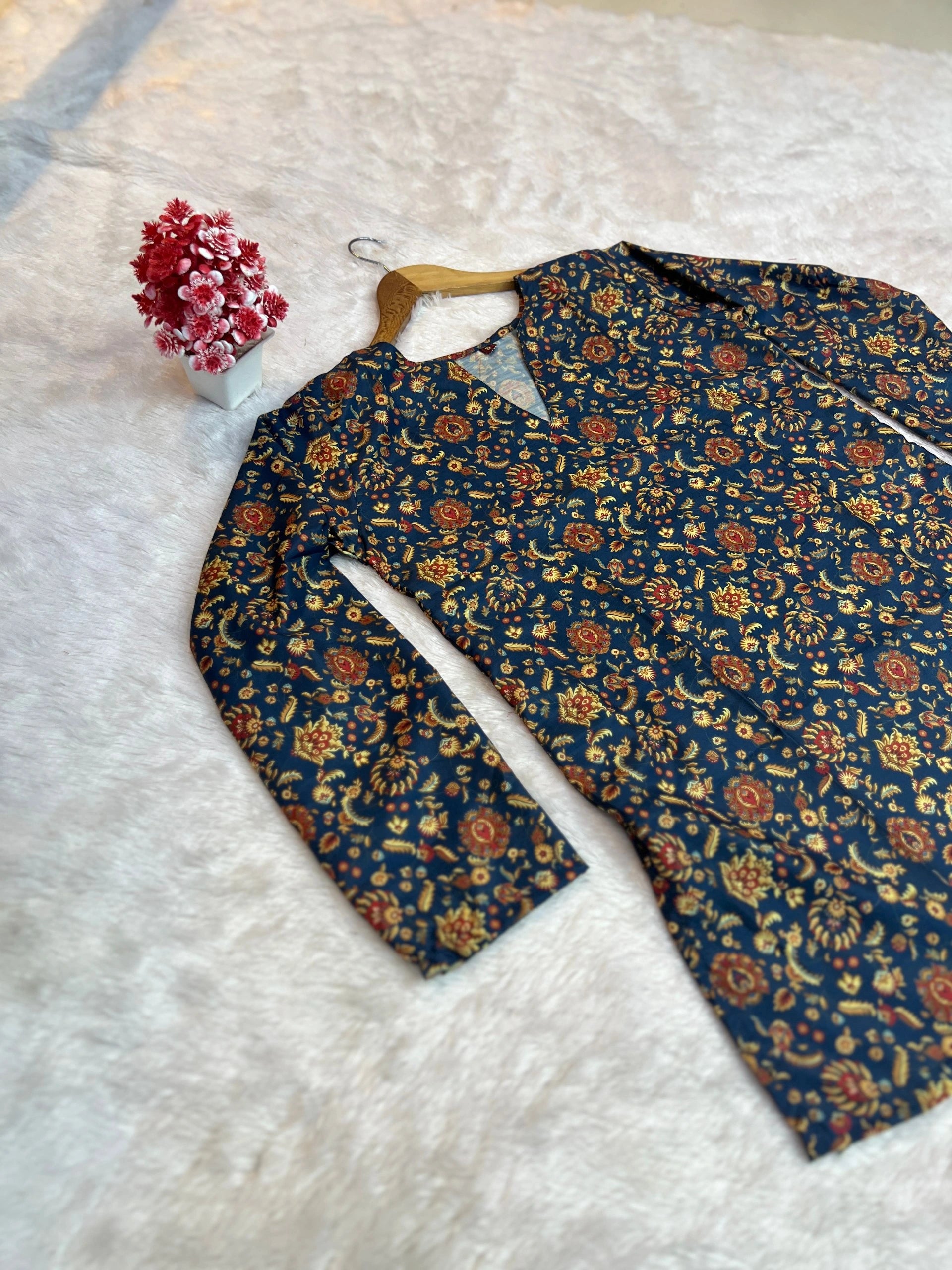 Floral-patterned shirt on a white textured surface with a small bouquet of flowers.