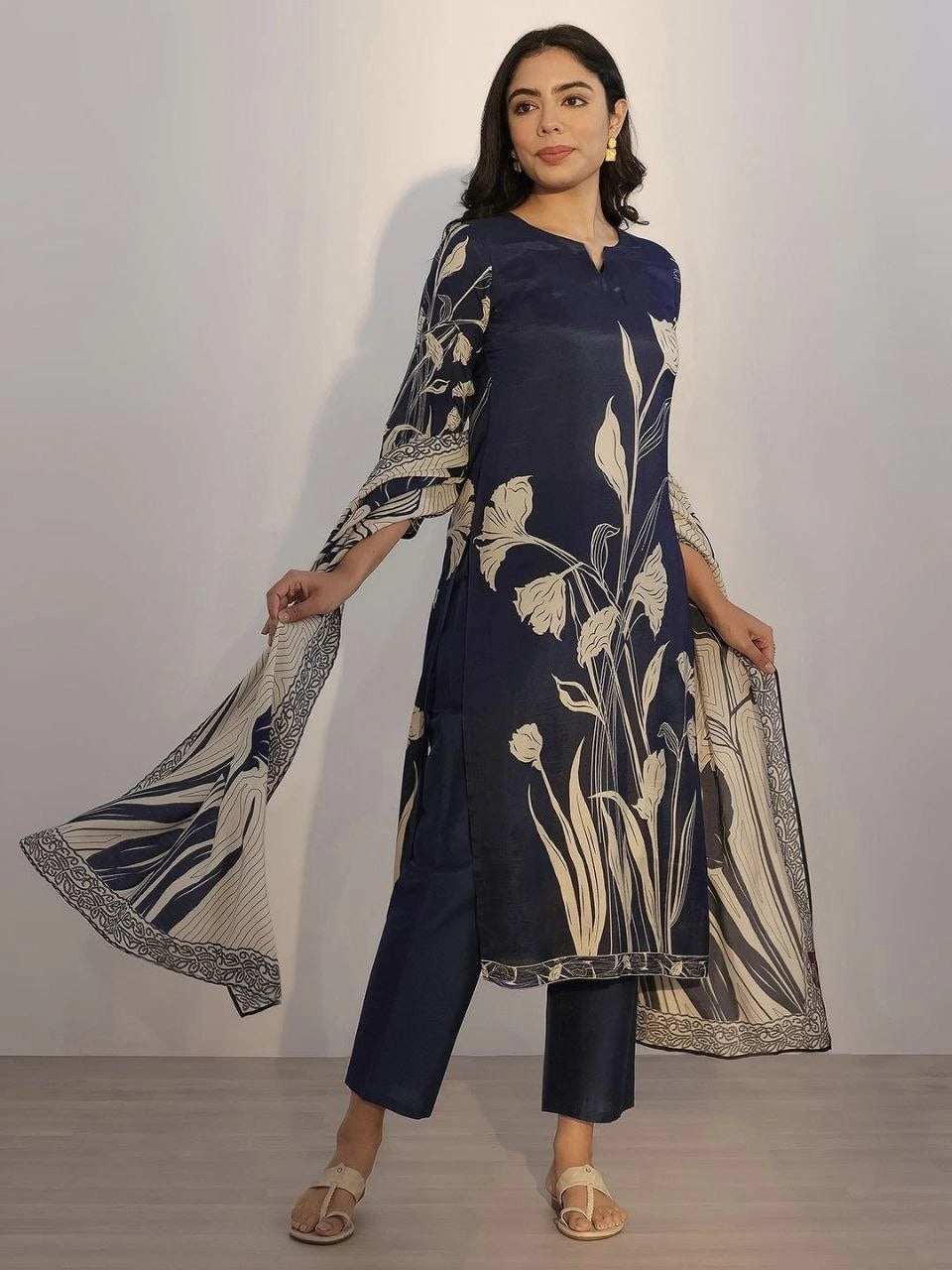 Woman wearing a navy blue outfit with floral patterns against a plain background