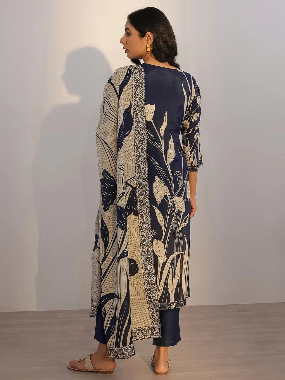 Woman wearing a navy and beige floral patterned outfit with a plain background