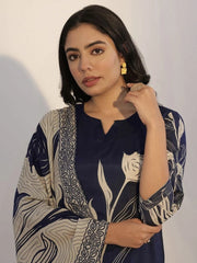 Woman wearing a navy blue and beige patterned outfit with gold earrings against a plain background