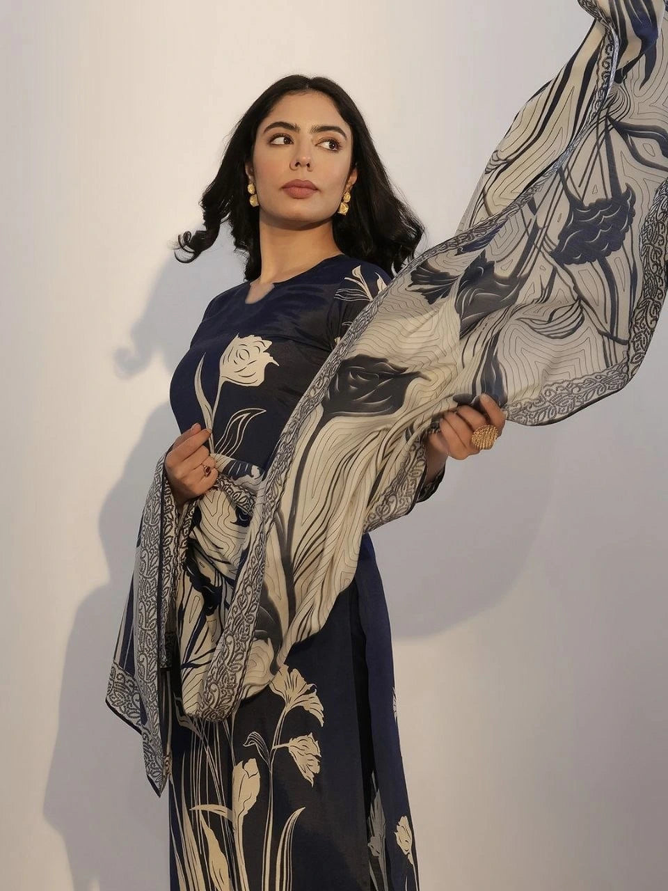 Woman holding a floral-patterned fabric against a plain background