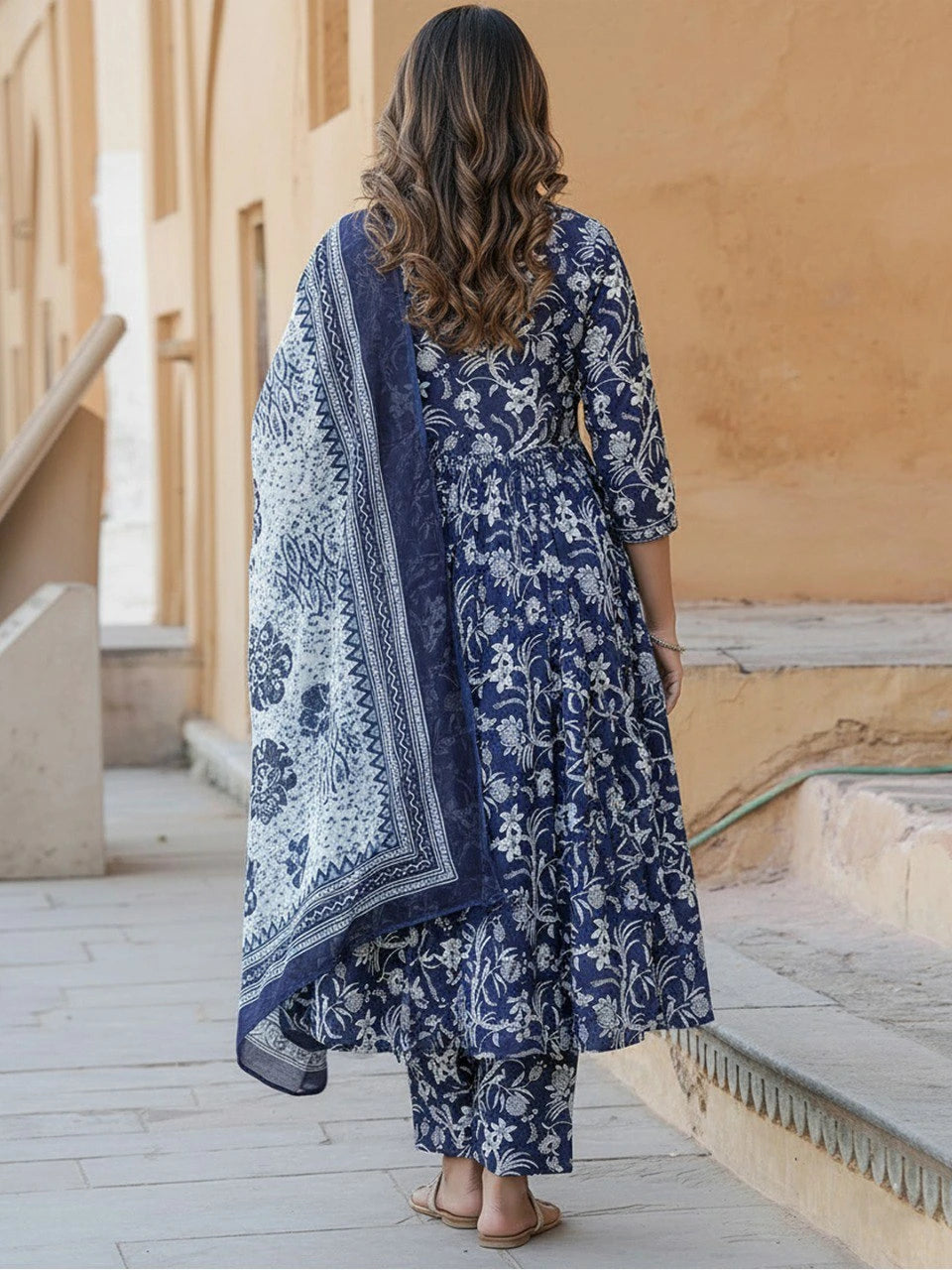 Woman wearing a blue floral dress and dupatta in an outdoor setting.