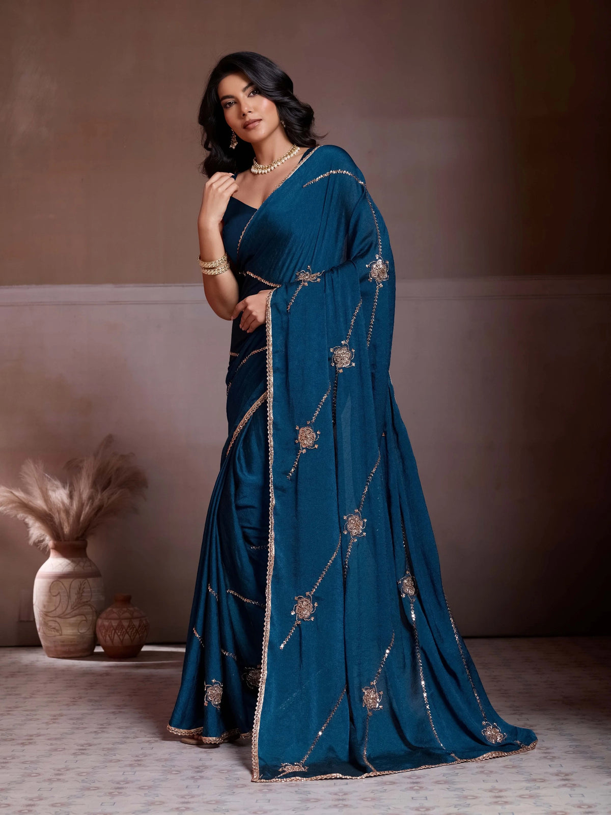 Woman in a blue saree with gold embroidery against a neutral background