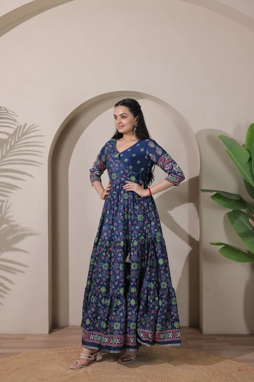 Woman wearing a blue floral dress standing in front of an archway with plants.