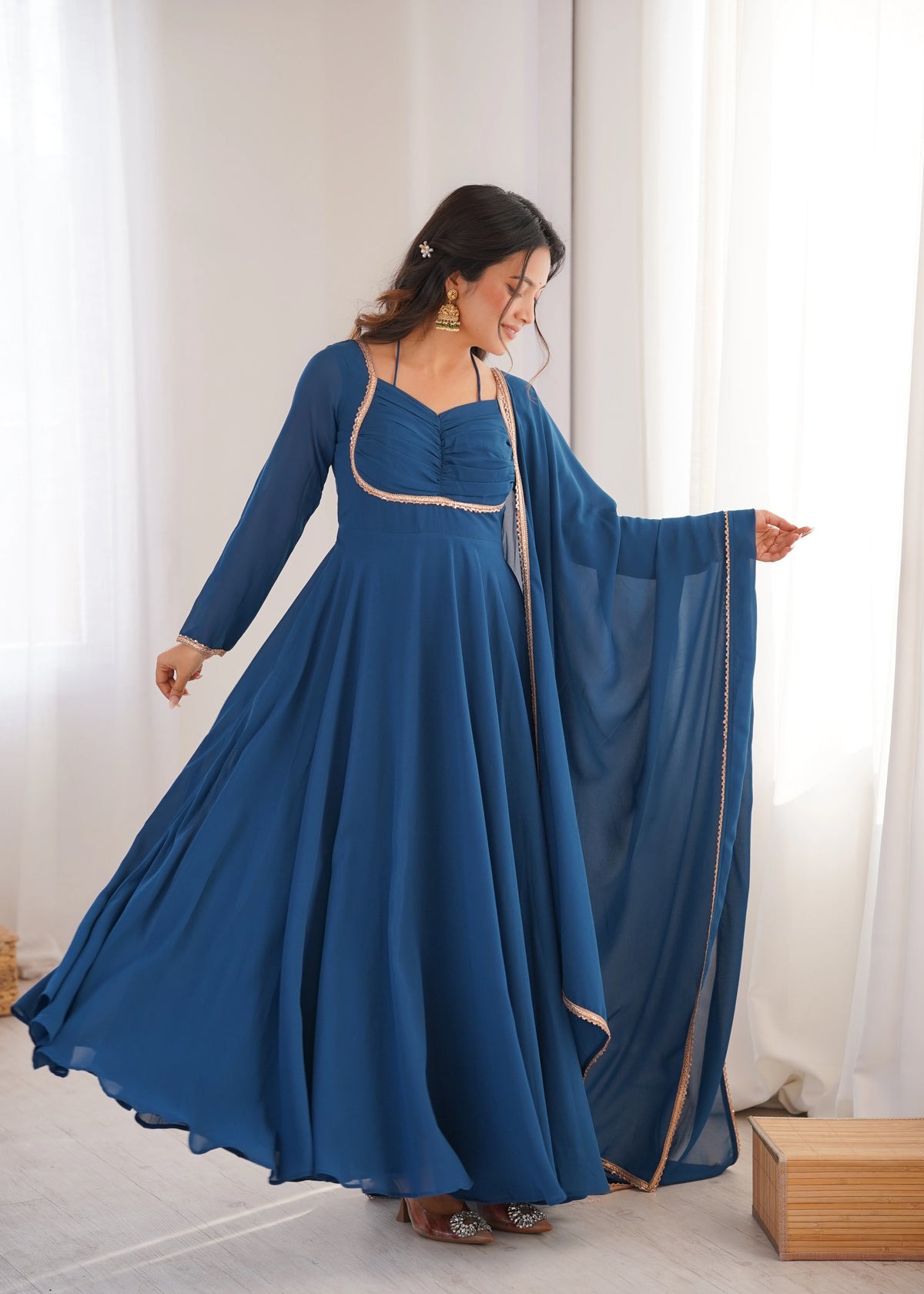 Woman wearing a blue dress with a matching dupatta in a bright room.