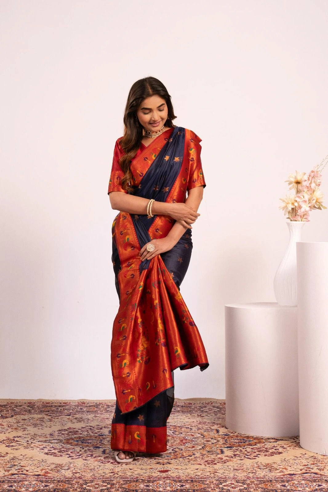 Woman wearing a traditional saree with a red and blue pattern on a white background