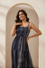 Woman wearing a navy patterned dress standing in an archway.