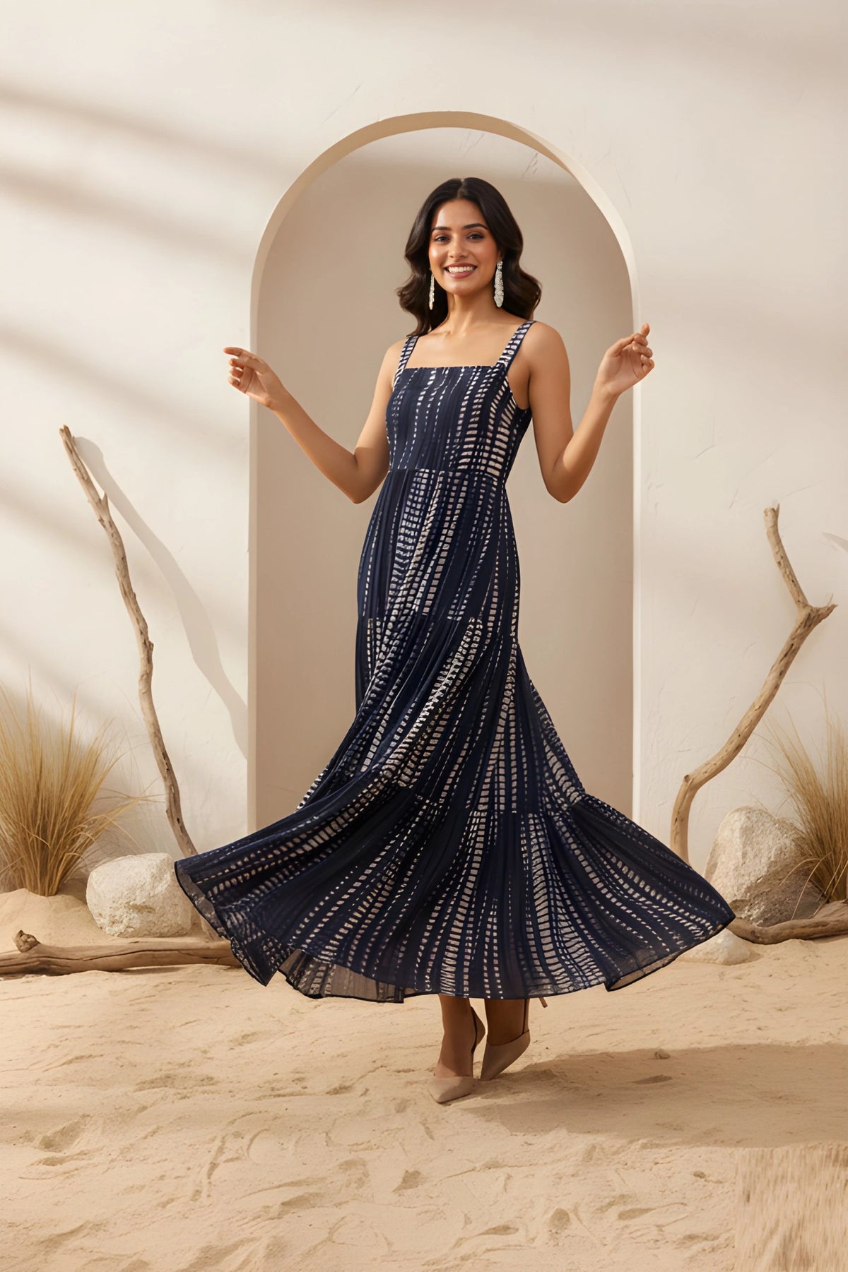 Woman in a navy blue dress standing in a desert-like setting with sand and rocks.