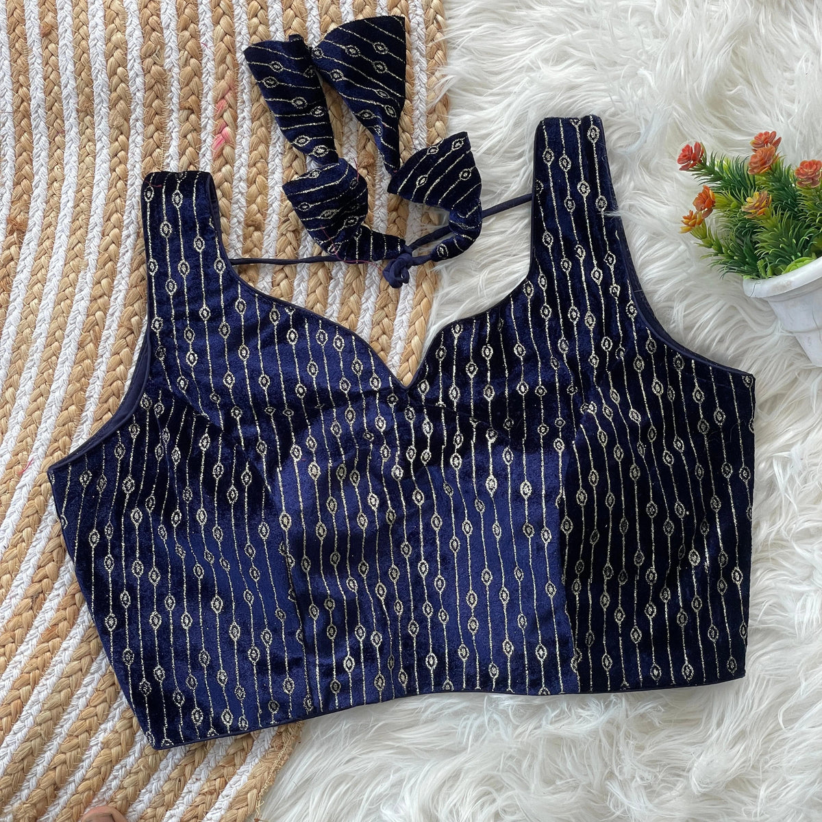 Navy blue patterned bikini top on a textured surface with a small plant in the corner.