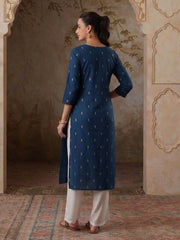 Woman wearing a blue kurta with white pants in an ornate room.