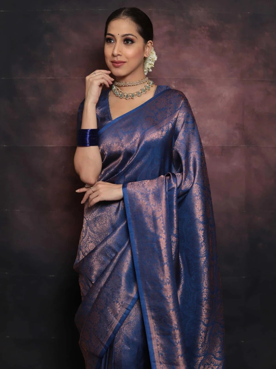 Woman wearing a blue saree with a dark background
