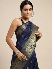 Woman wearing a navy blue saree with gold embroidery on a beige background