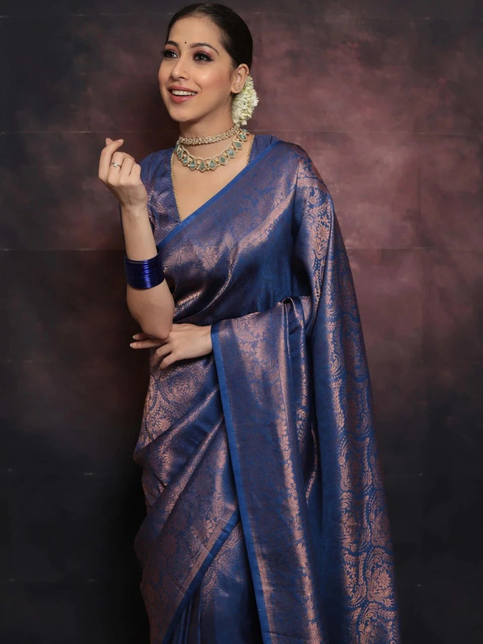 Woman wearing a blue saree with a dark background