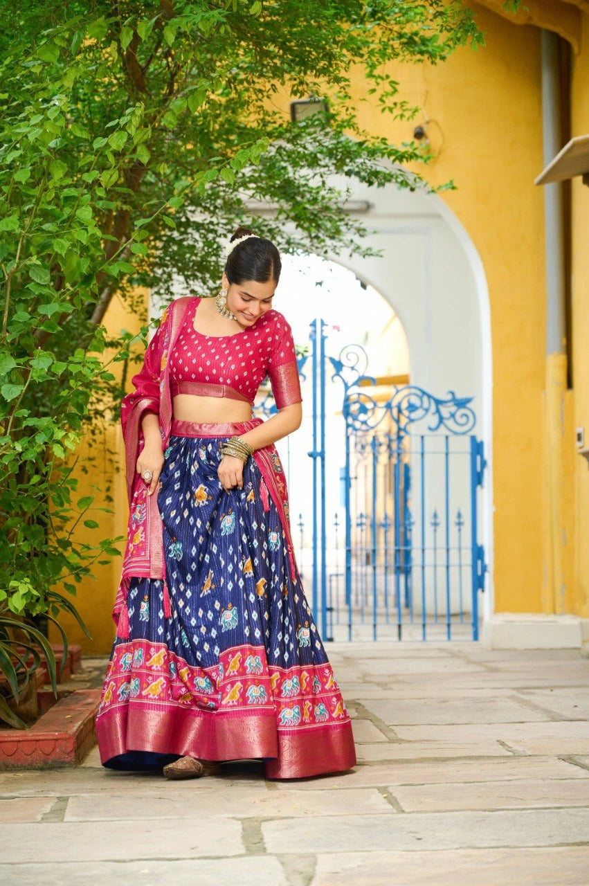 Woman in traditional Indian attire standing in front of a yellow building with an archway.