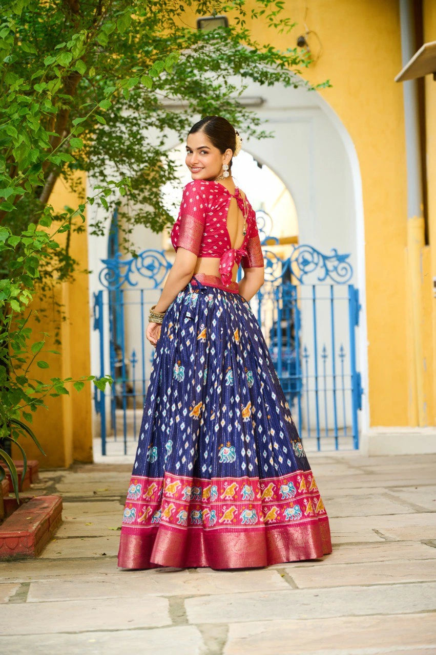 Woman in a traditional outfit standing in front of a yellow wall with an archway.