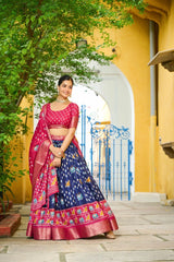 Woman in a traditional outfit standing in front of a yellow building with an archway.