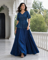 Woman wearing a blue traditional outfit standing on a balcony with greenery in the background