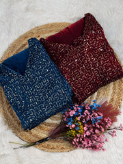 Two fabric samples, one blue and one red, on a woven mat with dried flowers.
