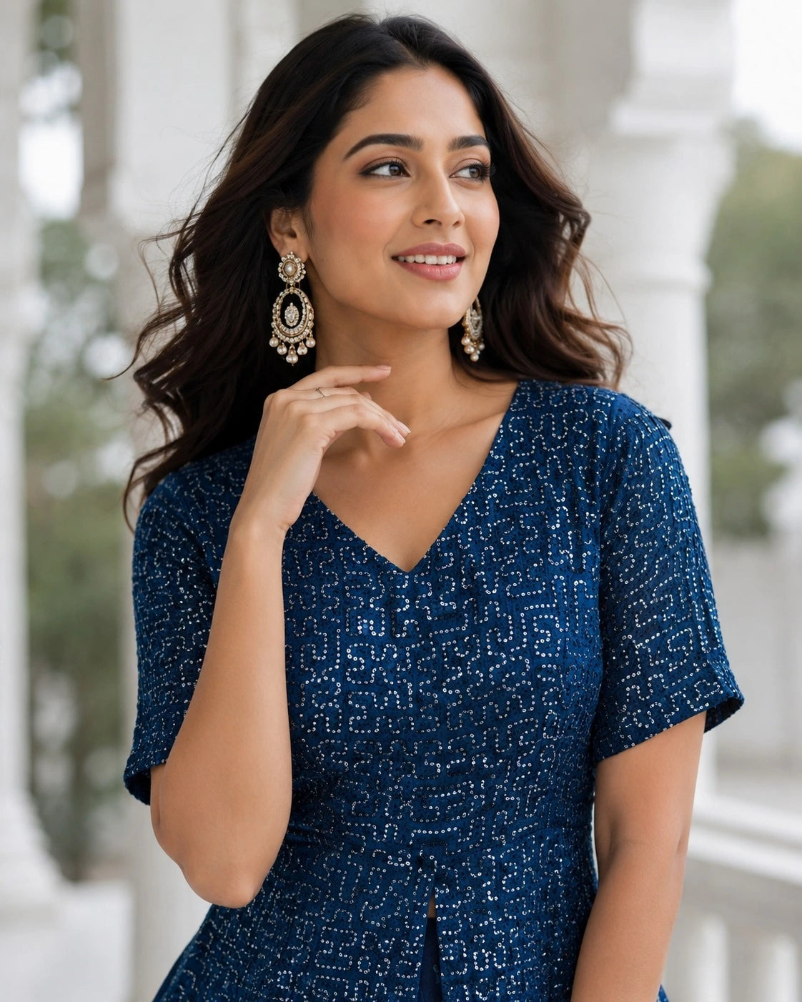 Woman wearing a blue patterned dress with earrings, standing outdoors.