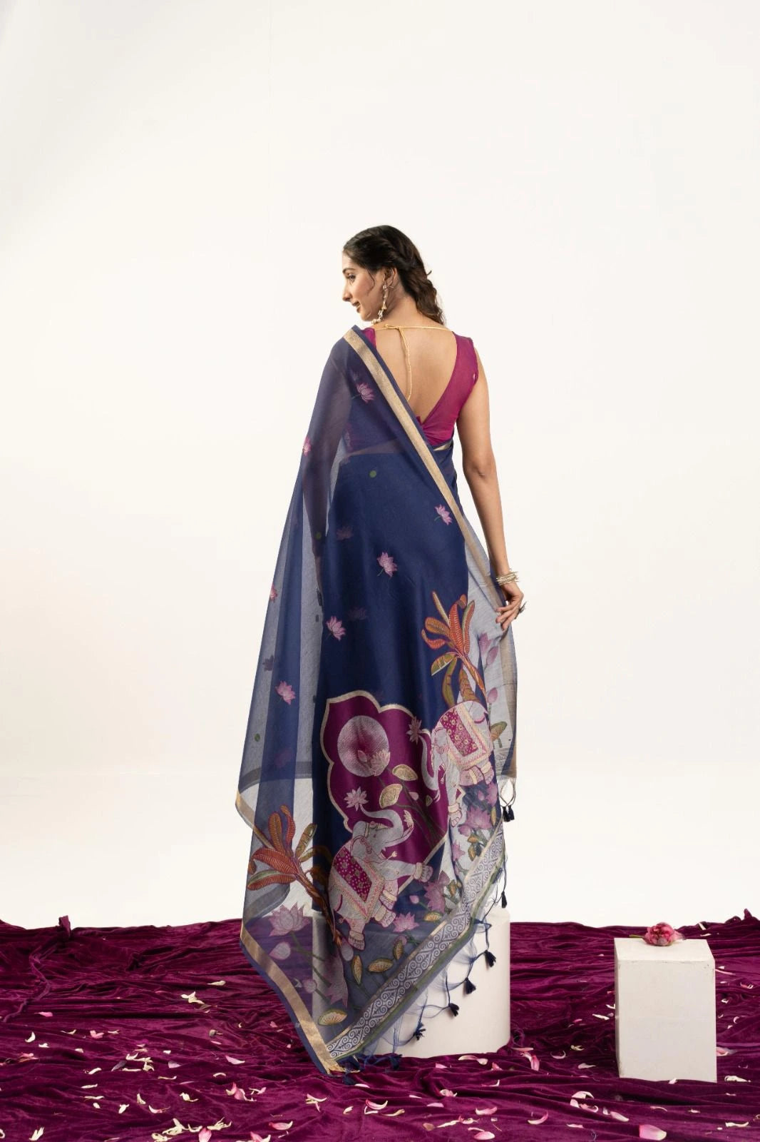 Woman wearing a blue saree with floral patterns on a white background