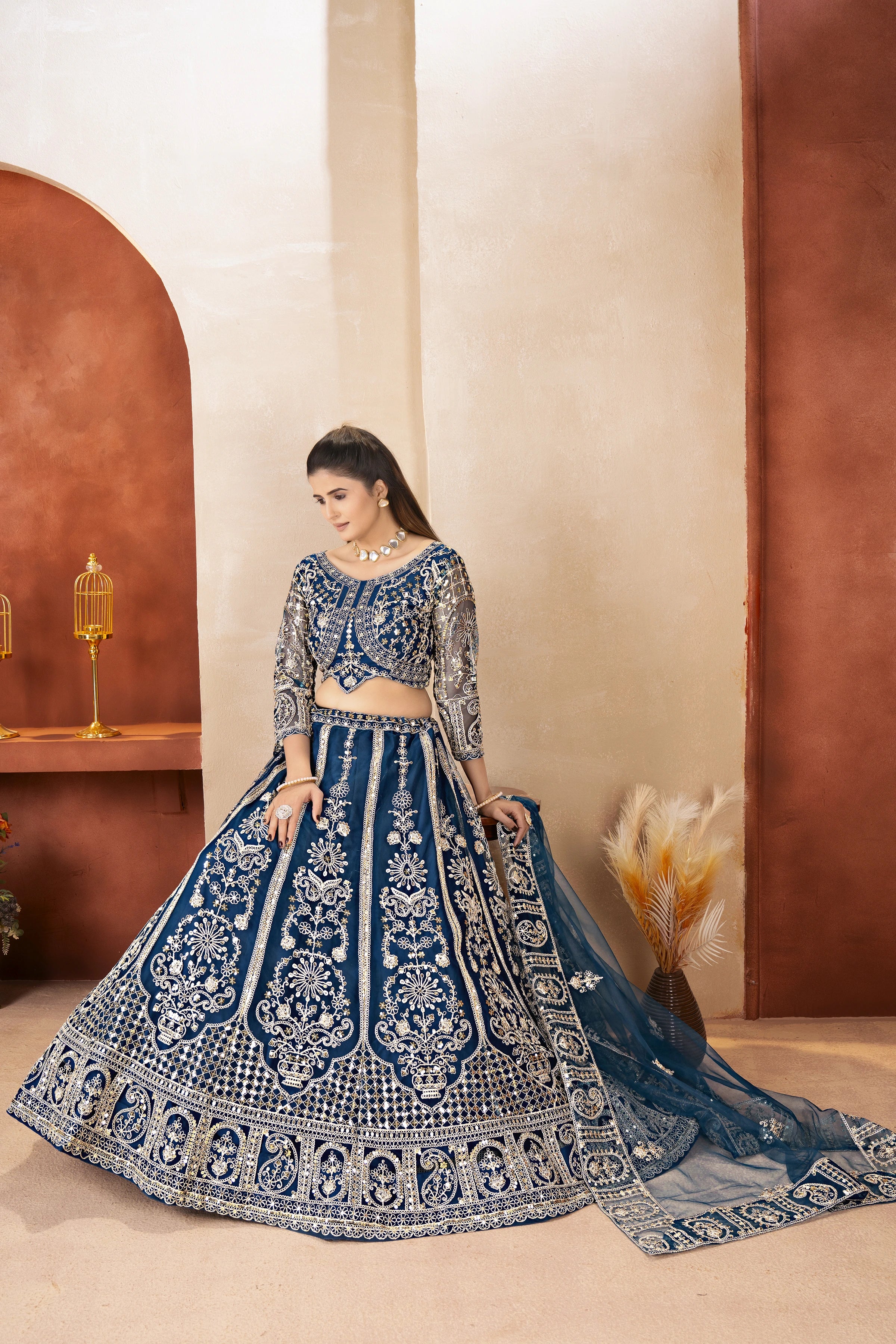 Woman in a blue embroidered traditional outfit standing against a neutral background