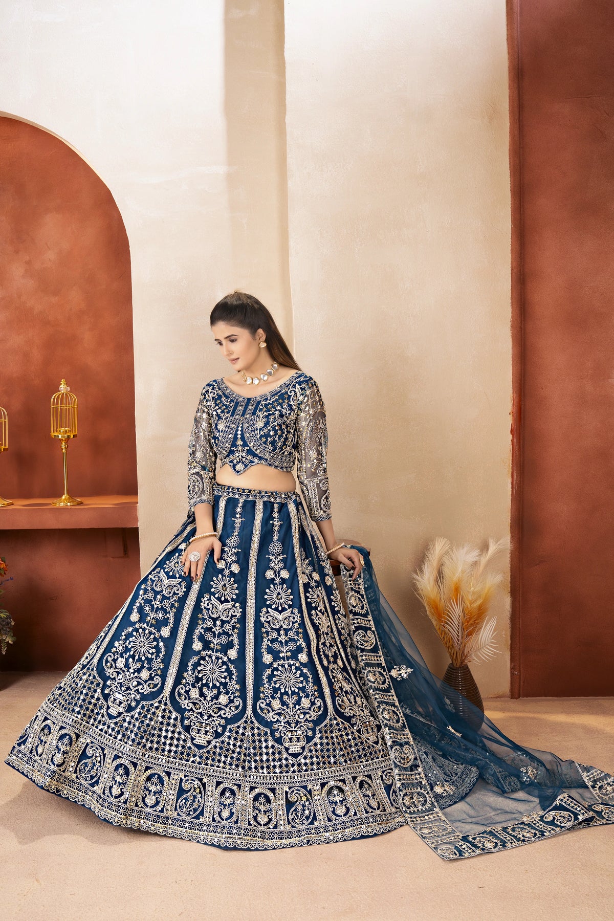 Woman in a blue embroidered traditional outfit standing against a neutral background