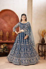 Woman in a blue and silver embroidered traditional outfit standing in a decorated room.