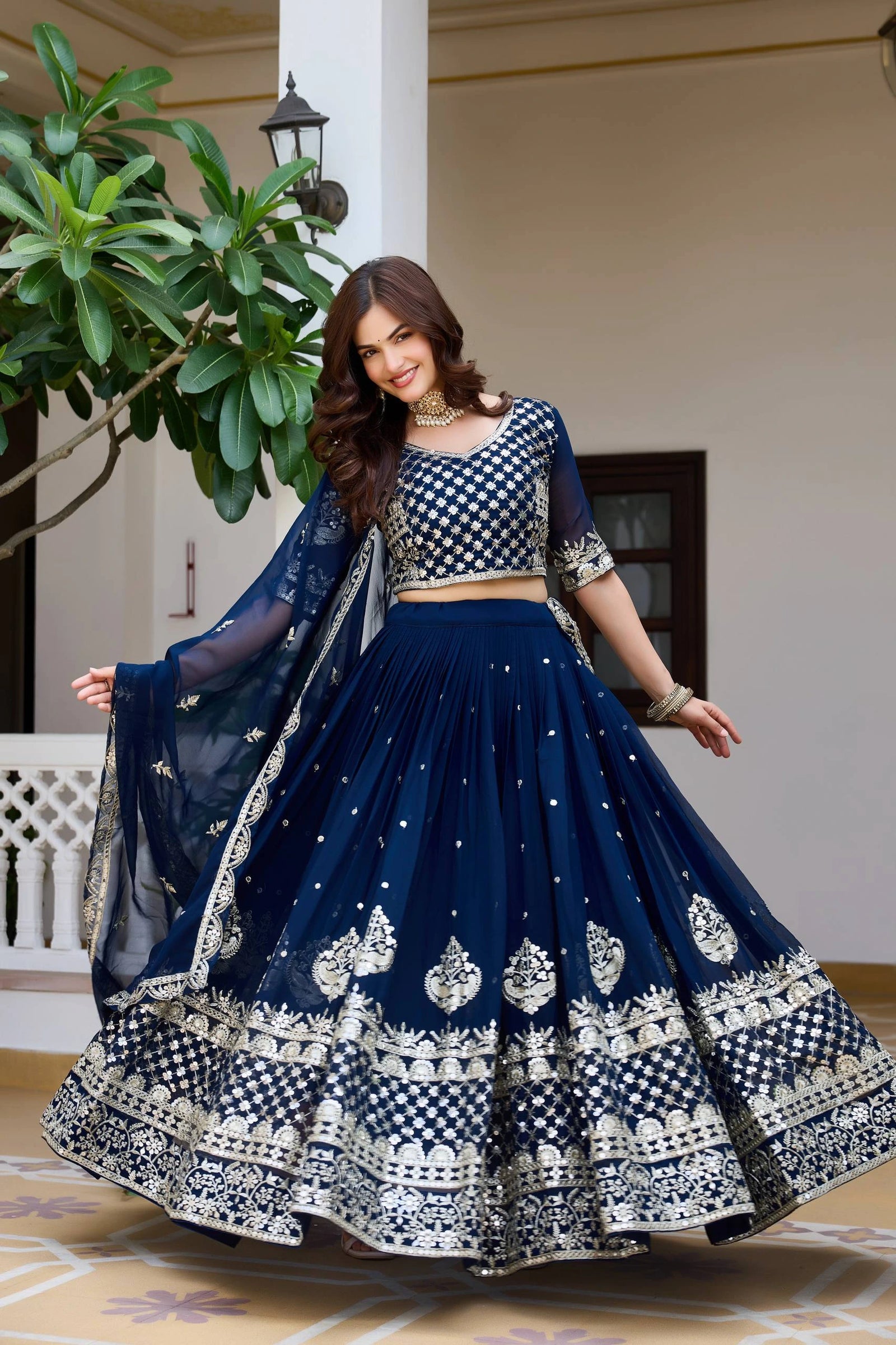 Woman in a traditional navy blue and white embroidered outfit standing indoors.