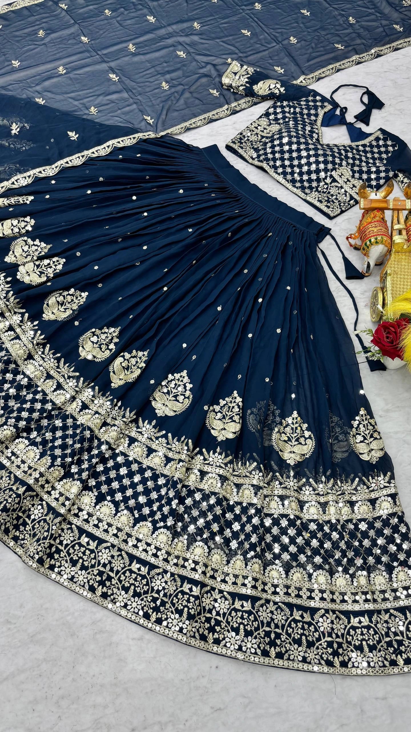 Navy blue embroidered lehenga with intricate patterns on a light gray surface.