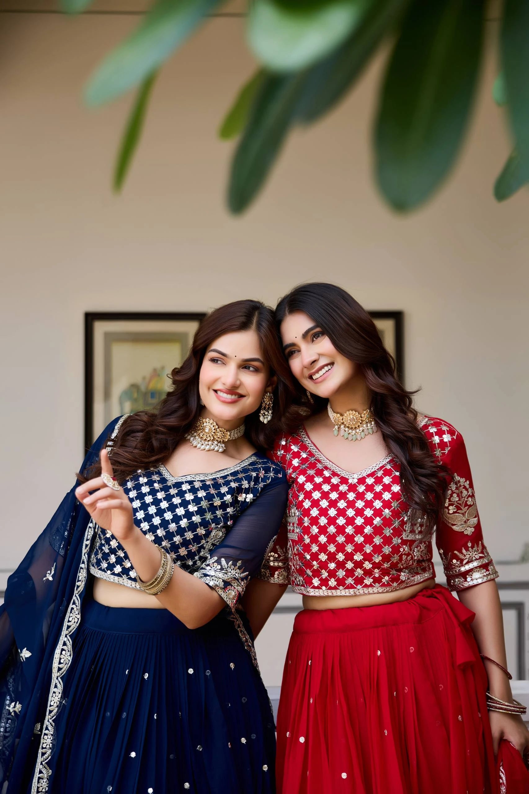 Two women in traditional outfits standing close together indoors.