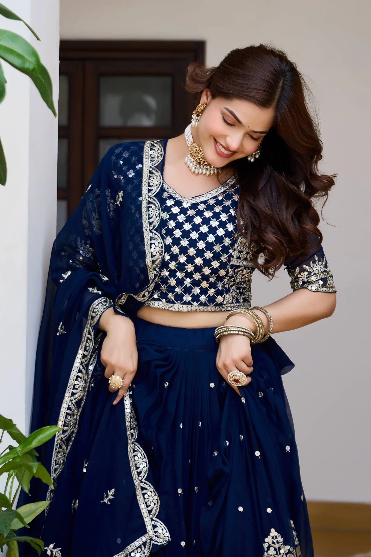 Woman in a traditional navy blue and silver embroidered outfit standing indoors.