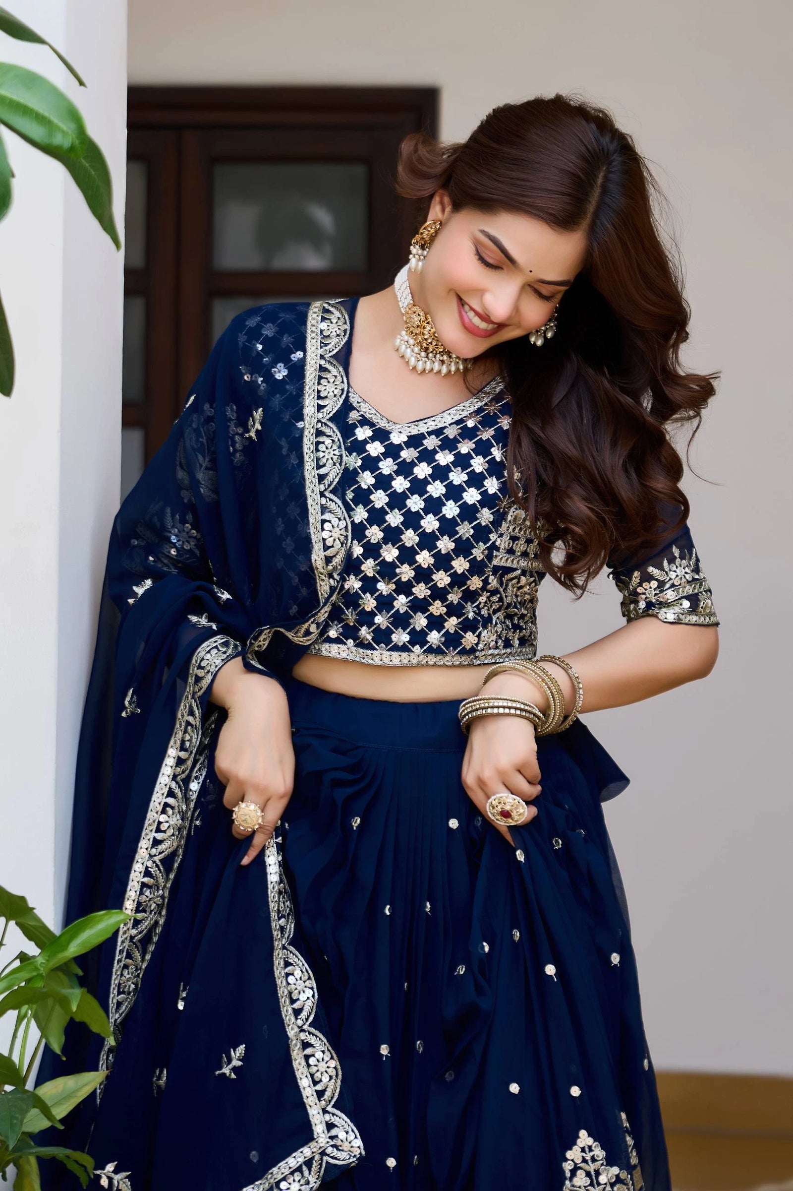 Woman in a traditional navy blue and silver embroidered outfit standing indoors.