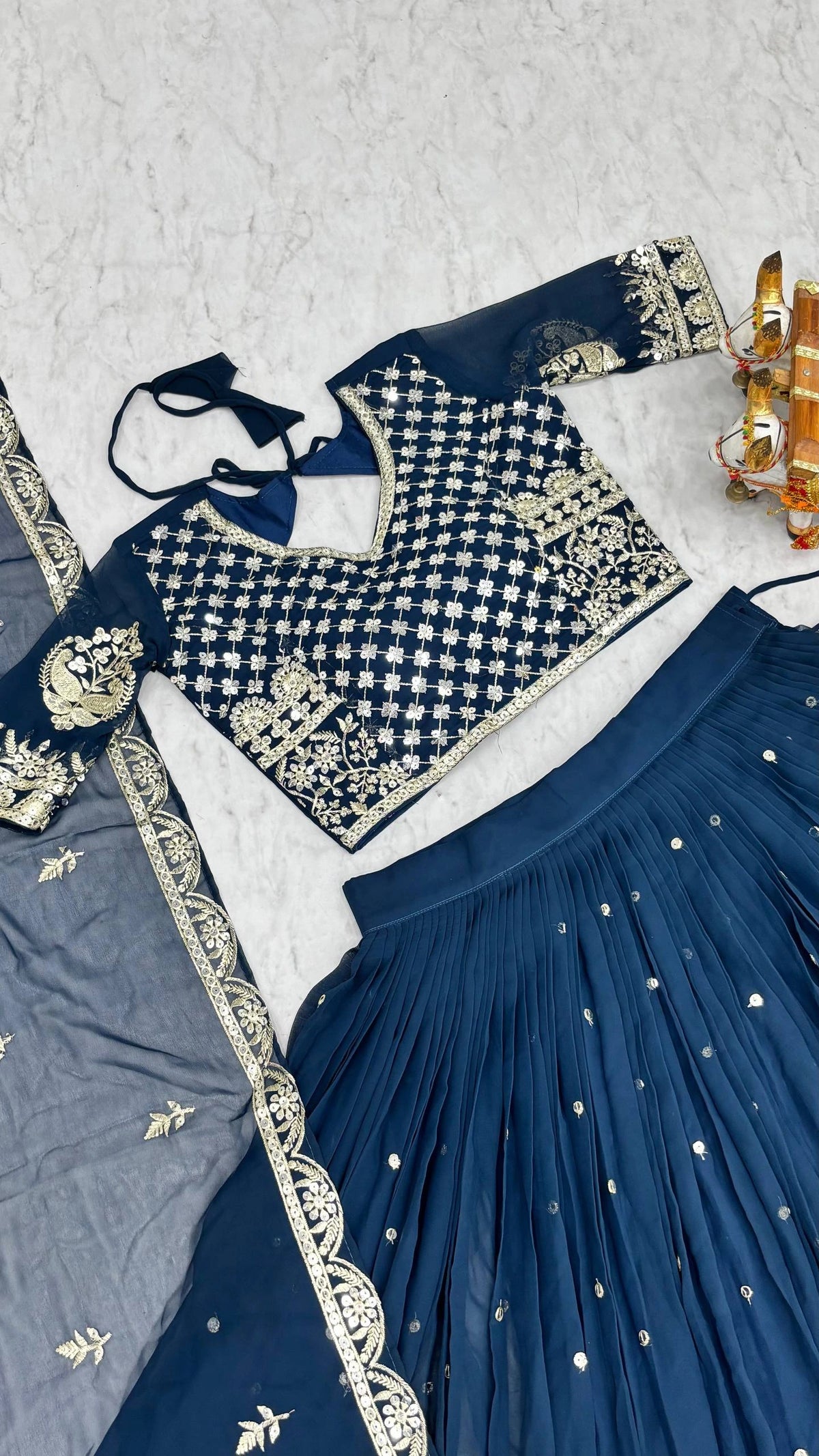 Navy blue traditional outfit with intricate white embroidery on a light gray background