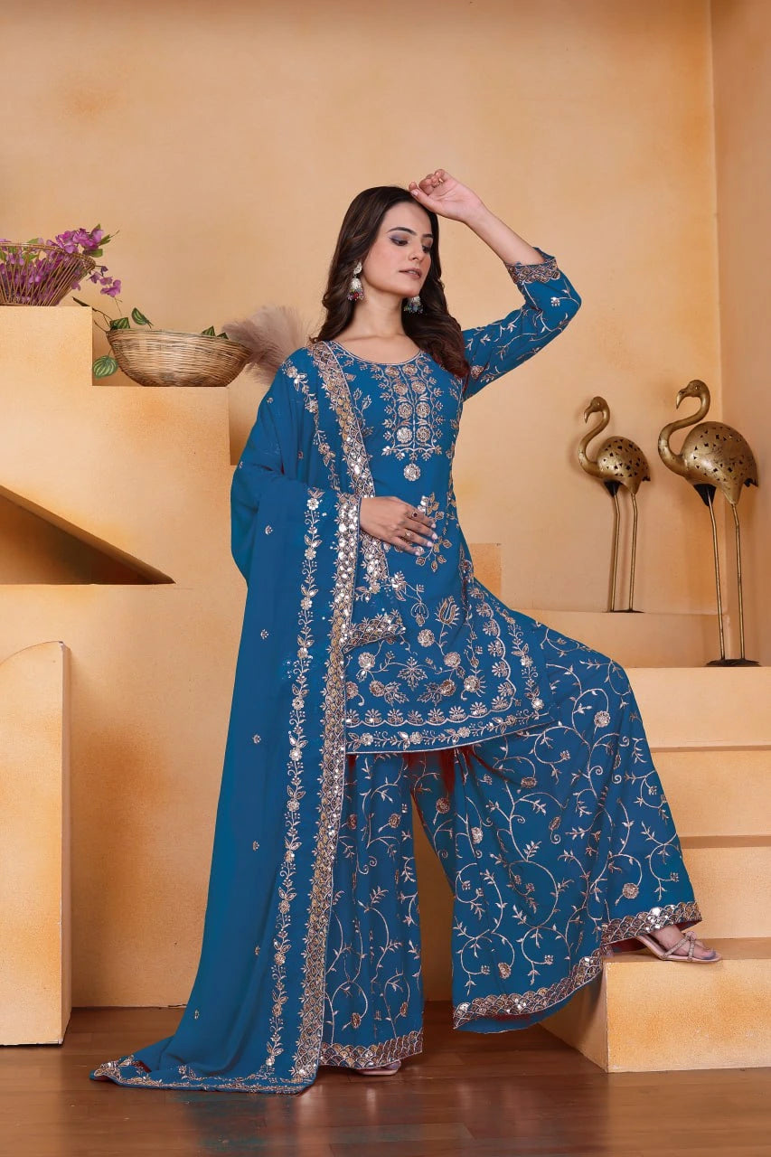 Woman in a blue embroidered traditional outfit standing on a staircase.