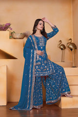 Woman in a blue embroidered traditional outfit standing on a staircase.