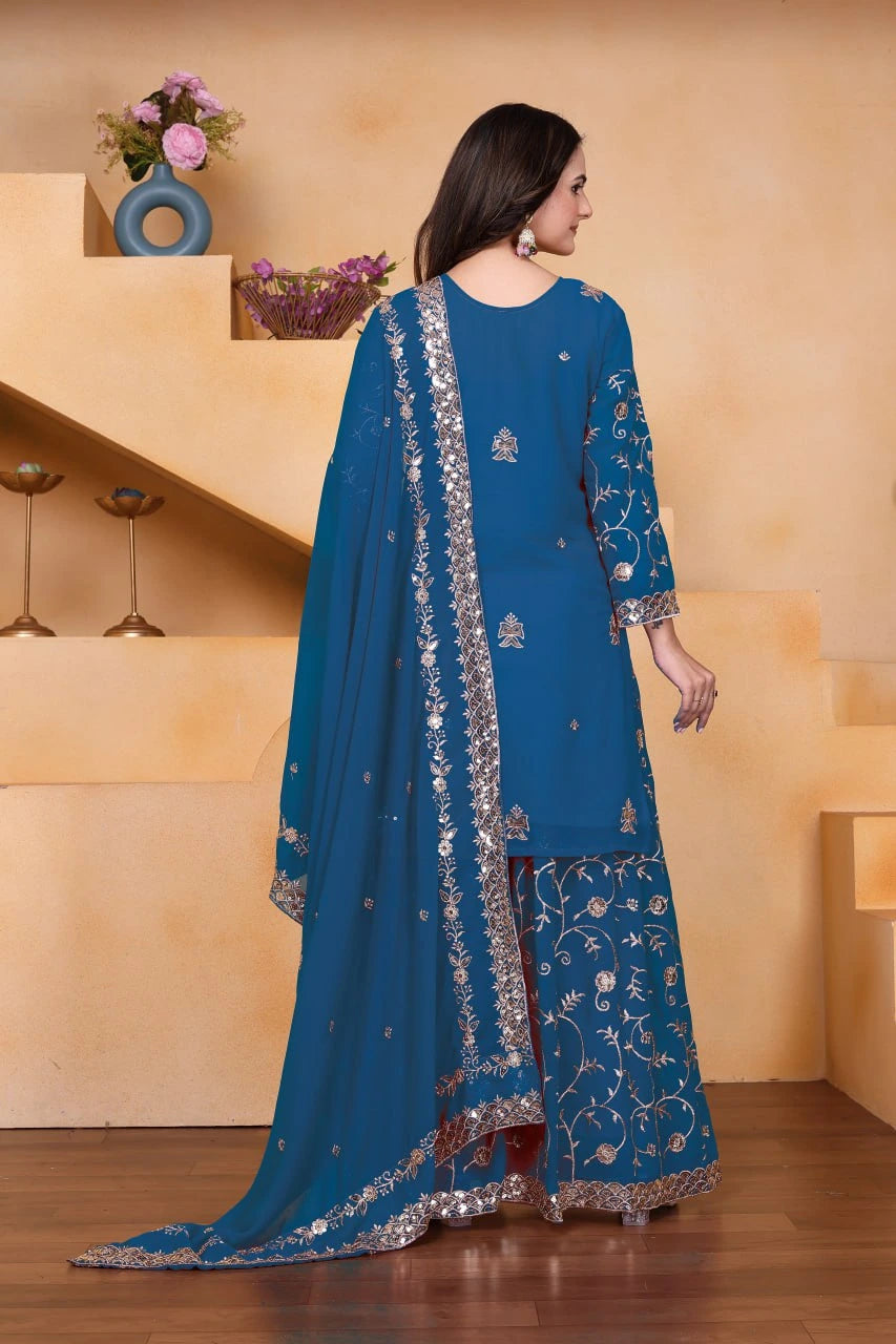 Woman wearing a blue embroidered outfit with a matching dupatta in an indoor setting.