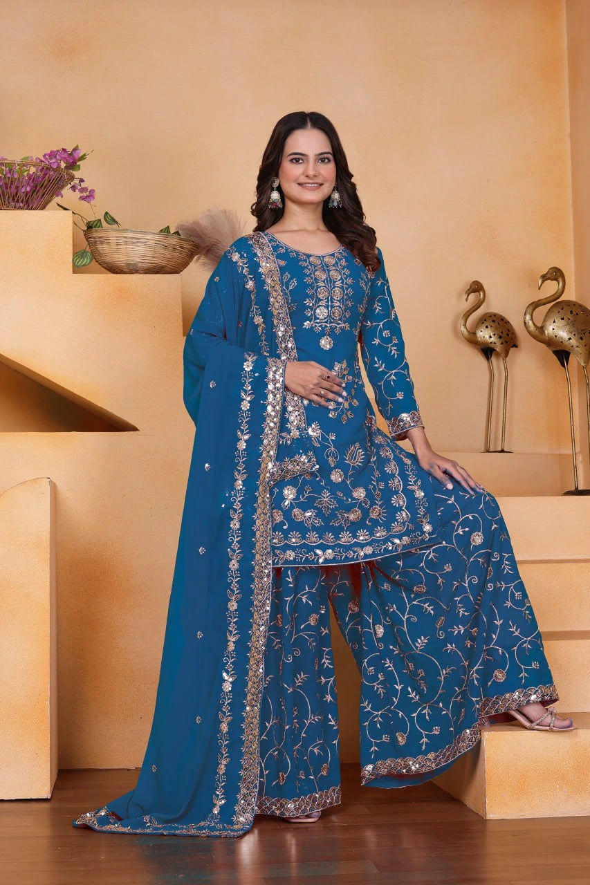 Woman in a blue embroidered traditional outfit standing on steps with a neutral background